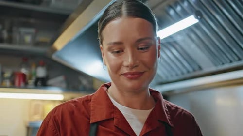 Smiling Woman Chef Talking to Unknown Colleague at Modern Kitchen Closeup