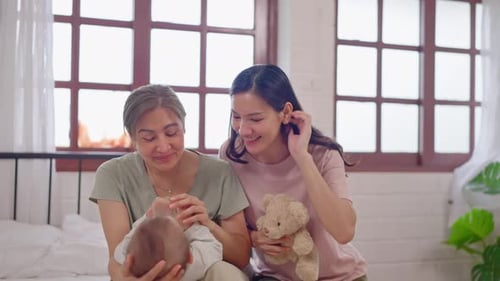 Asian lesbian couple caring for and raising their baby boy at home.