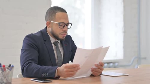 Adult Reads Papers at Office Desk