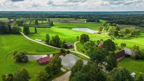 Small community of homes surrounding pond reflecting cloudy sky, aerial hyperlapse