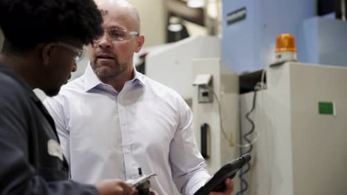 Machine Shop Supervisor and Worker Examining Machine Part Blue Collar