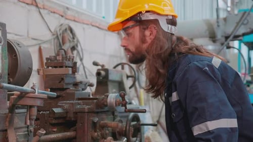 Young caucasian engineer man operating lathe machine for preparing production at factory industrial.