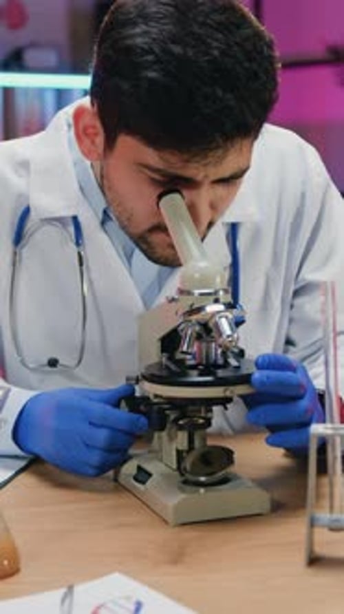 Young Adult Male Scientist Using Microscope in Laboratory
