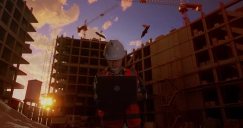 Asian Male Engineer Working On A Laptop And Looking Around At Construction Site