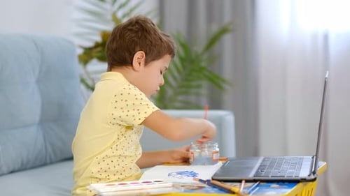 Boy Diligently Painting At His Art Desk