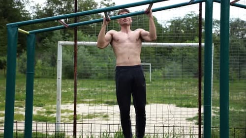 Athletic Man Doing Pull-Ups in Urban Park
