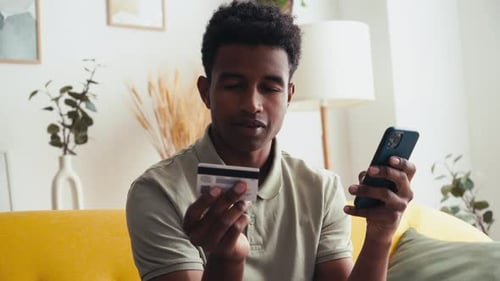 Young Adult Using Phone and Credit Card at Home