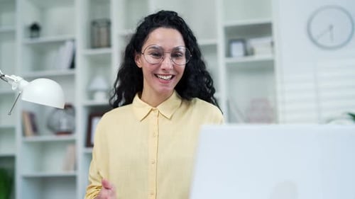 Close up. Confident young woman talking on a video call using a laptop while sitting in a home offic