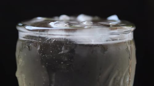 Close Up of Ice Cubes Falling Into a Glass of Water