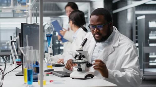 Scientists Working with Microscope and Computer in Laboratory