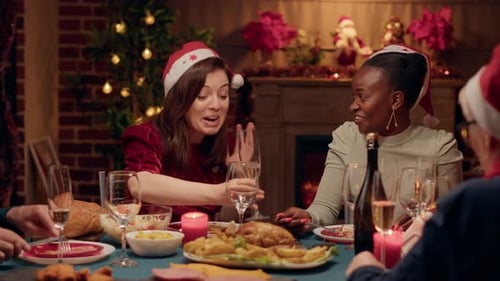 Excited Woman Discussing with Close Friend at Christmas Dinner While Drinking Champagne