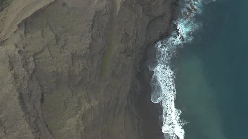 Drone top down shot of waves bounce on rocks at the coast