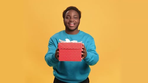 Kind African American Man Giving Gift Box to Camera Portrait of Black Man in Studio Bday Concept