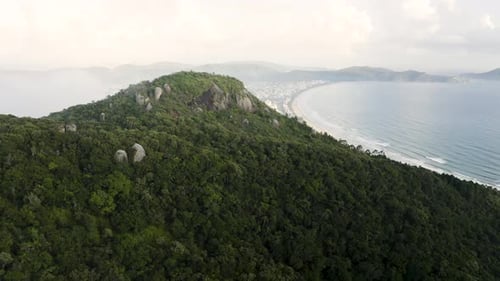 Drohne distanziert an einem Sommertag einen wunderschönen tropischen Waldberg mit einem paradiesischen Strand dahinter