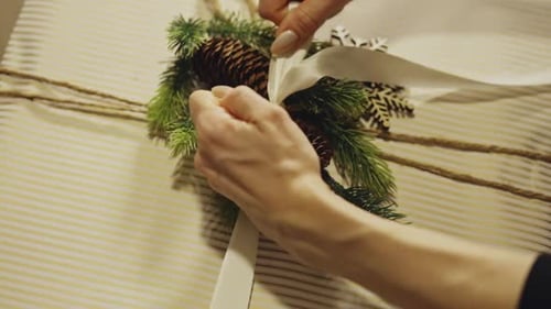 Person Wraps Christmas Present With White Ribbon. Close-up Shot