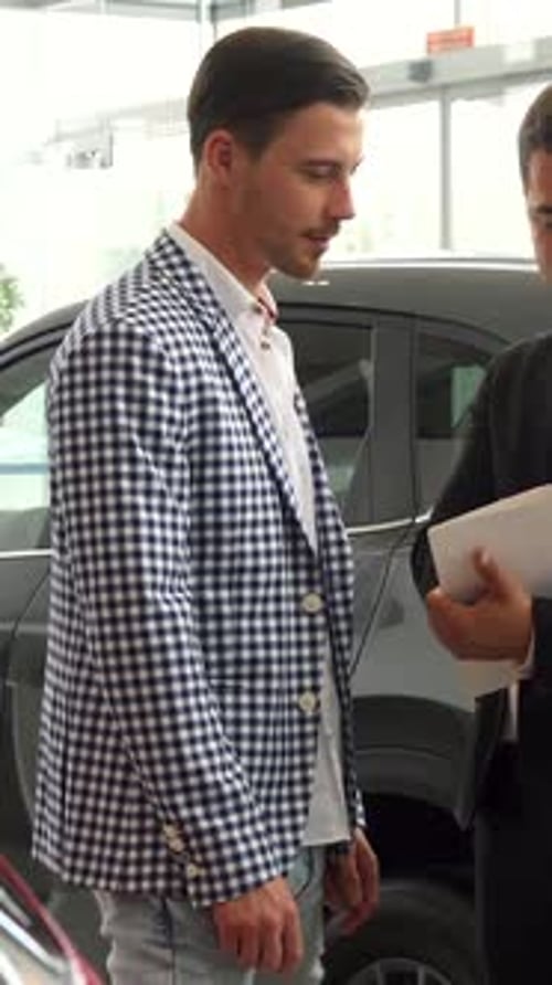 Serious Men Finalize a Car Purchase Agreement in a Sleek Dealership