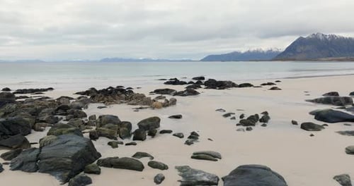 Secluded Shoreline at Lofoten Islands Pristine Beach with Rocky Outcrops and Distant Mountains