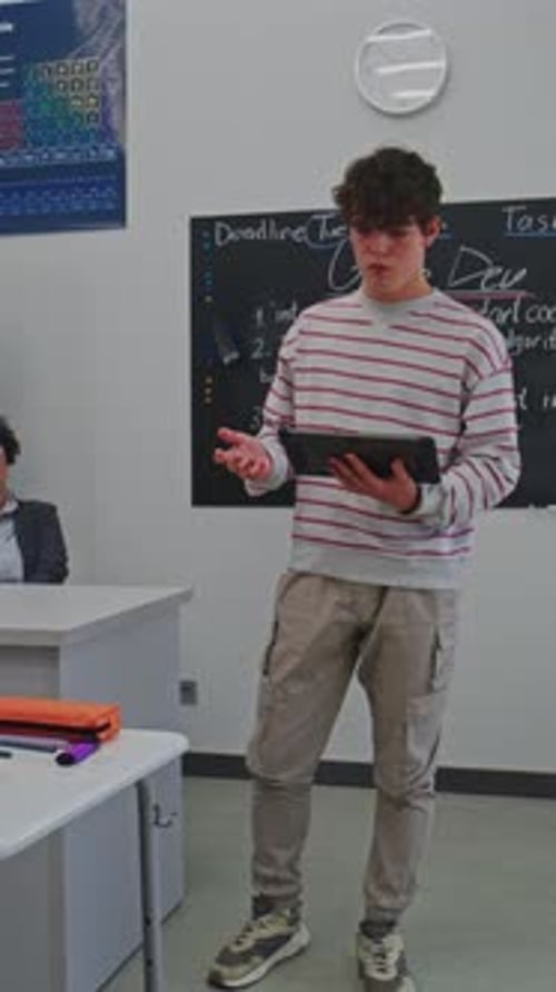 Young Man Confidently Delivers Presentation Using Digital Tablet in Modern Classroom