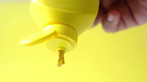 Yellow Mustard Dripping from Squeeze Bottle Close Up