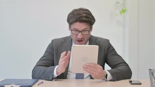 Mature Man Anxiously Using Tablet in Office