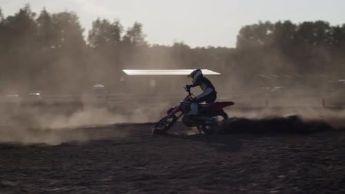 Trained Biker in Helmet Drifts with Racing Motorcycle in Field