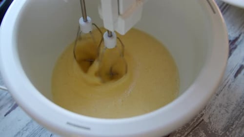 Electric Mixer Whipping Cake Batter in White Bowl