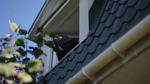Une silhouette furtive observant tranquillement son environnement depuis un haut point de vue sur le toit