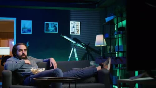 Man Lounging on Couch Watching TV with Popcorn