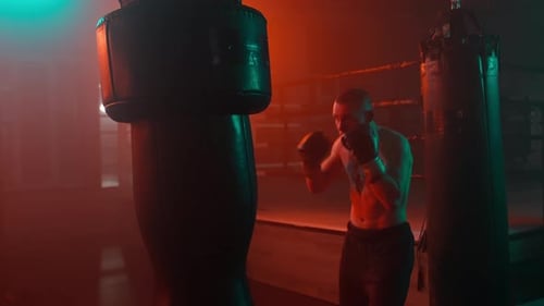 Man Training Boxing with Punching Bag at Night