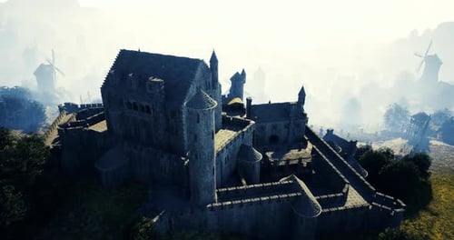 Historic Stone Castle Surrounded By Fog and Windmills at Dawn