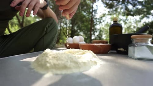 Person Adding Ingredients to Flour Outdoors
