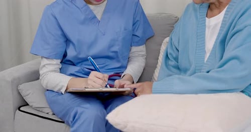 close up view of female nurse taking notes while elderly cancer patient gestures during home