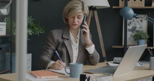Portrait of Entrepreneur Speaking on Mobile Phone and Working with Laptop in Office Room