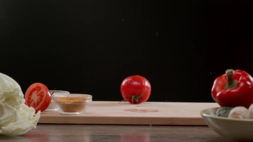 One Tomato Falls Onto the Chopping Board Causing Splashes of Water to Fly Around