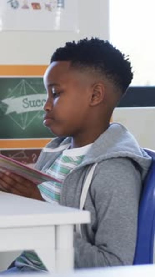 Vertical video: Hand reaching, student in gray hoodie bringing striped notebook, studying at desk