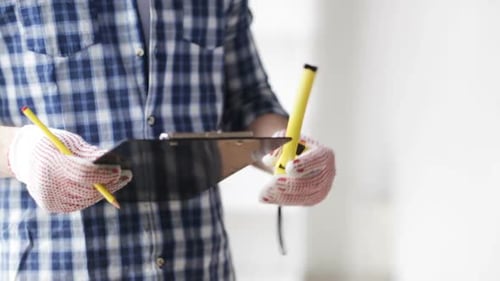 Adult Male Measuring with Tape Measure and Writing