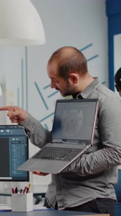 Supervisor de proyectos hombre que sostiene el portátil y señala en la pantalla