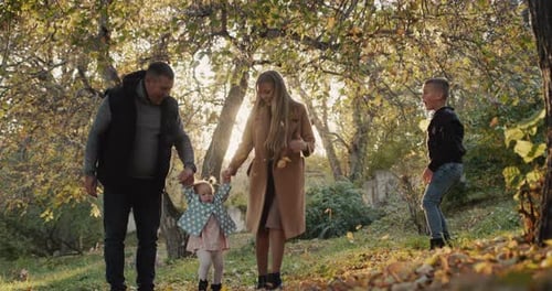 Family with Two Children Have Fun in Autumn Park