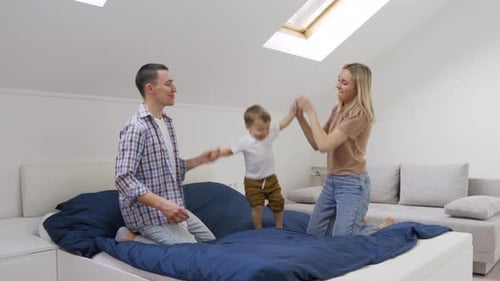 Playful family jumping on the bed together indoors