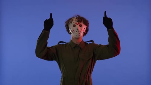 Man in White Mask Pointing Fingers Up on Blue Background with Red Neon Light Image of Jason Voorhees