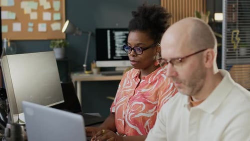 Concentrated Diverse Developers Coding on PC in Open Space Office