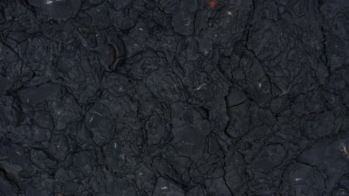 Dark black basalt rock solidified lava field cracked rugged surface
