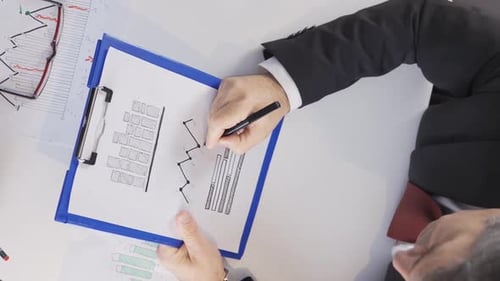 Adult Annotating Financial Charts in an Office Setting