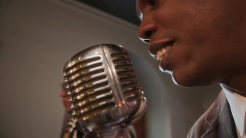 Man Sings Into Vintage Microphone, Saxophone Player