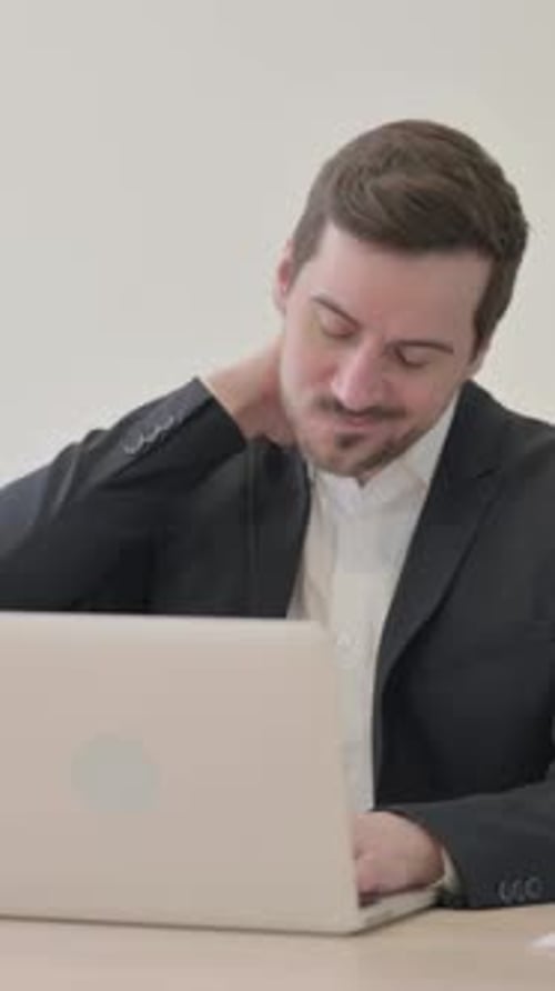 Stressed Man Massaging Neck While Using Laptop