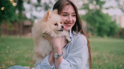 Woman Holding Pomeranian Dog Smiling in Park