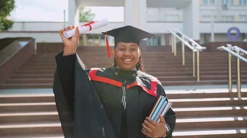 African American Female Student Celebrating Graduation Near College