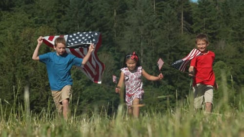Children running in field holding American flags