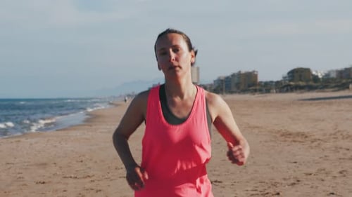 Woman running on ocean beach. Front view