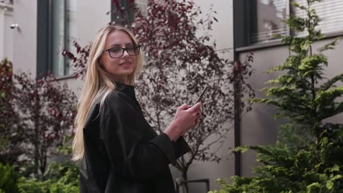 Young Woman Using Phone in Urban Garden